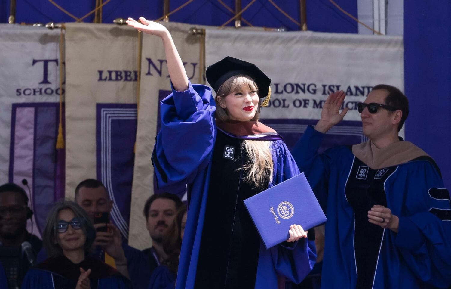 Artisti Taylor Swift pitelee tyytyväisenä kädessään kuvataiteen tohtorin tutkinnon todistusta.