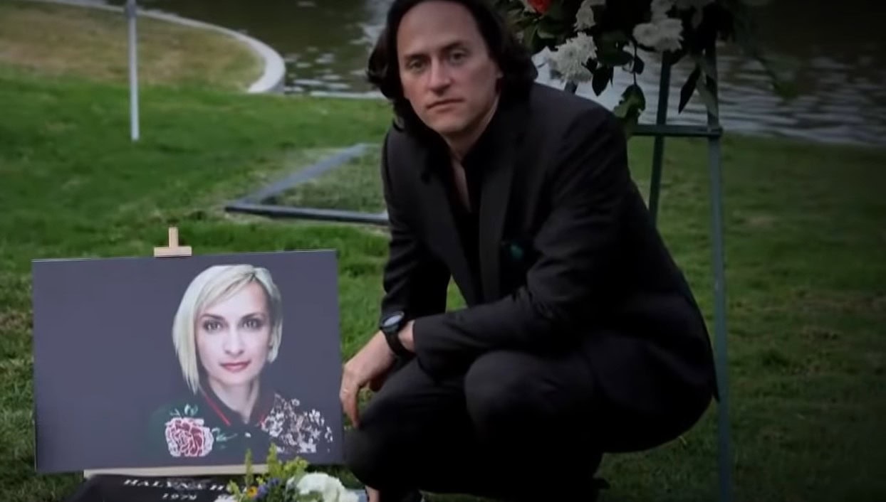 Matt Hutchins vaimonsa Halyna Hutchinsin hautajaiskuvan vieressä.