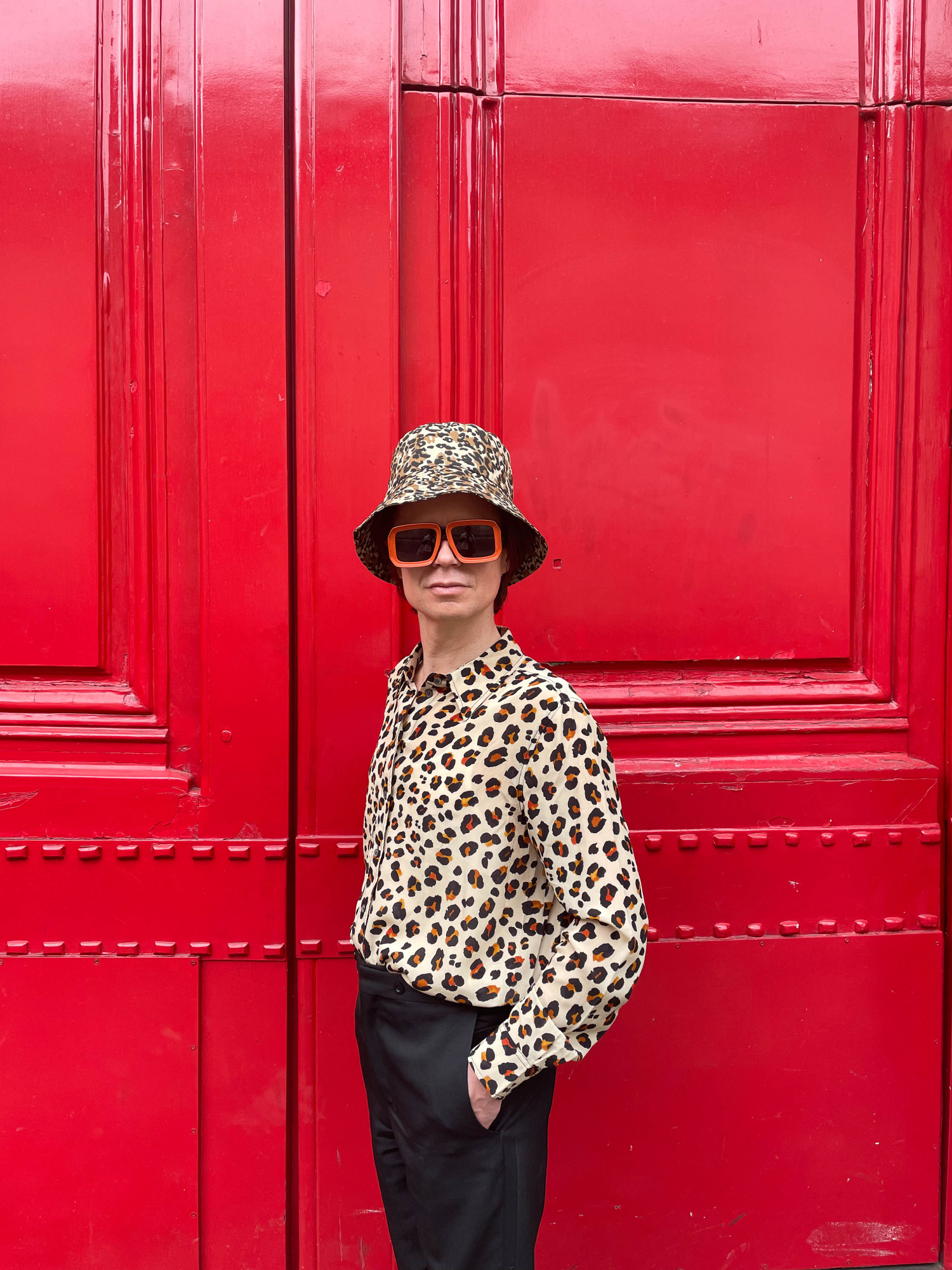 Leopardikuvioinen hattu ja paita luovat yhdessä näyttävän kokonaisuuden. Lookin kruunaavat isot oranssit aurinkolasit.